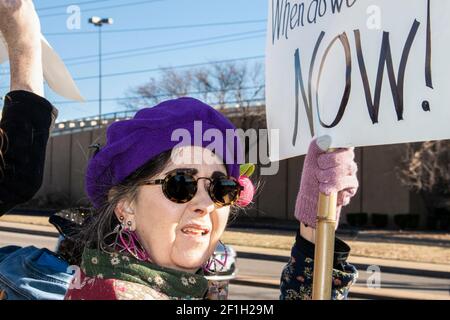 01-04-2020 Tulsa USA - Worried looking senior citizen woman with colorful clothing and peace earrings at war protest with sign Stock Photo