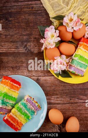 Colorful cut cake with brown eggs for Easter on wooden background. Stock Photo