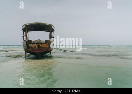 Shallow atoll sandbanks with lonely fisherman boat on low tide Nungwi beach in the Indian Ocean on the Zanzibar island, Tanzania. Exotic countries tra Stock Photo