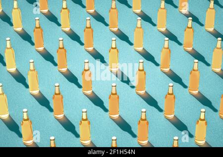 Rows of full beer bottles against light blue surface. Mockups of full glass bottles without label, long shadows. Retro drink bottle concept. Stock Photo