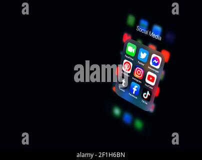 2020: Apple  iPhone black smartphone showing the Social Media icons bundle, in dark Stock Photo