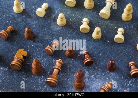 A closeup shot of partially standing and fallen wooden chess pieces from both sides on a blue surface Stock Photo