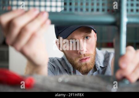 a concentrated man in fixing a chair Stock Photo