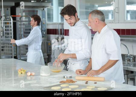 apprentice talking to chef during work in the kitchen Stock Photo