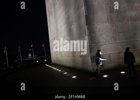 Washington, USA. 08th Mar, 2021. The U.S. Capitol Building seen behind visitors at the base of the Washington Monument on the National Mall at night, in Washington, DC, on Monday, March 8, 2021, amid the coronavirus pandemic. The U.S. Senate over the weekend approved a version President Biden's $1.9 trillion COVID relief bill with his signature expected soon enacting it into law, as the confirmed coronavirus death toll in the United States hits 525,000. (Graeme Sloan/Sipa USA) Credit: Sipa USA/Alamy Live News Stock Photo