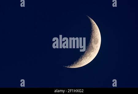 Waxing crescent moon in a dark blue night sky Stock Photo