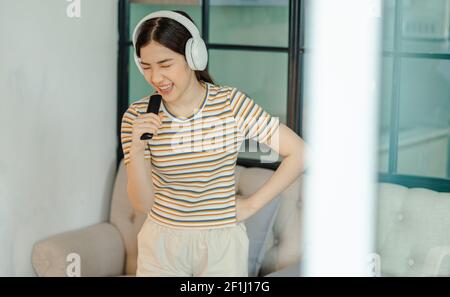 Beautiful Asian woman singing in the living room Stock Photo