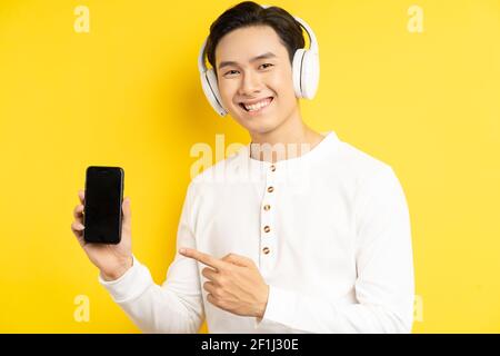 Asian businessman was wearing wireless headphones to listen to music and his finger was pointing at the cell phone he was holding Stock Photo