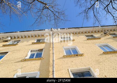 Old multistoried apartment building yellow brick facade. Old architecture low angle view Stock Photo