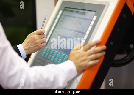 Industrial training. Engineer teaching to work on new computerized manufacturing equipment using CNC control panel. Selective focus. Stock Photo