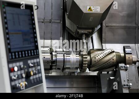 Gear shaft manufacturing process with CNC machining center. Selective focus. Stock Photo