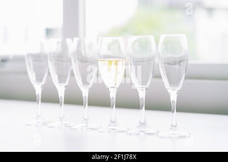 six glasses of wine on the table and only 1 with wine, concept of difference Stock Photo