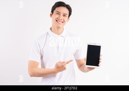 Cheerful young man standing on white isolated wall background. Looking at the tablet screen display camera. Stock Photo
