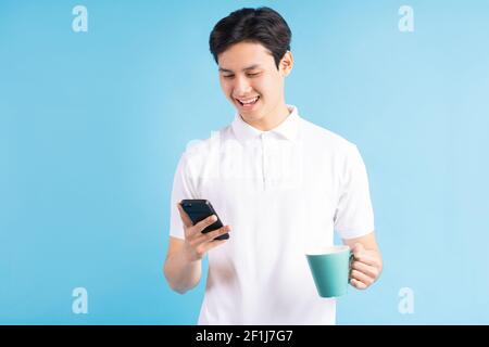 a photo of a handsome Asian man texting while drinking water Stock Photo