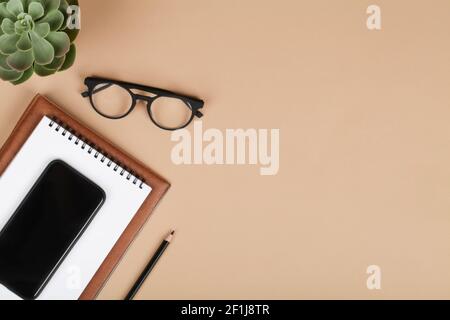 office table desk, workspace with mobile phone, notebook, pencil, green plant and eyeglass. Business background. Flat lay, top view.copy space Stock Photo