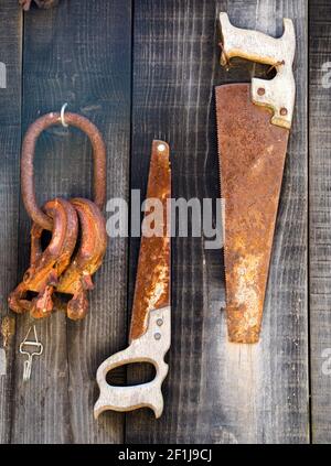 Old rusted vintage saw and tools hanging on a barn Stock Photo