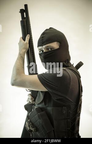 Thief, man armed with shotgun and bulletproof vest Stock Photo