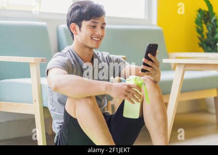 Asian man resting and using phone after exercising Stock Photo