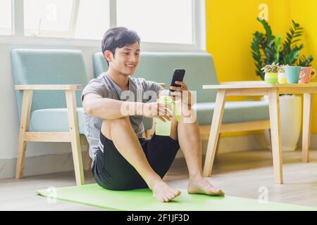 Asian man resting and using phone after exercising Stock Photo