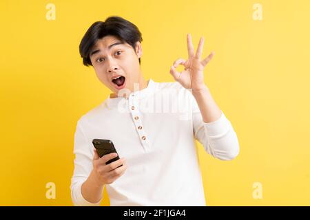 Asian man using his phone with a surprised face Stock Photo