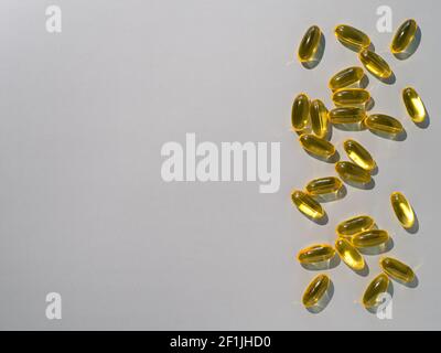 Vitamin D3, Omega or Evening Primula Oil gel capsules on neutral gray background. Top view or flat lay yellow liquid capsules with nutritional supplement oil. Copy space for text. Stock Photo