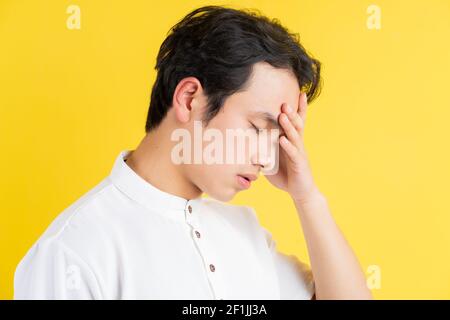 Portrait of young man having a headache on a yellow background Stock Photo