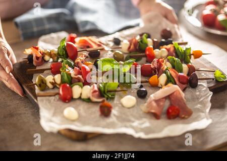 Female hands holding board with mini caprese skewers italian or mediterranean appetizer Stock Photo