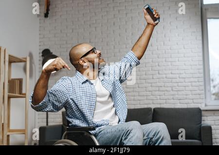 Disabled man sitting in a wheelchair and using Smartphone Stock Photo