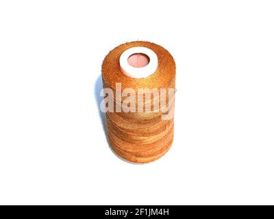 A large spool of brown sewing thread on a white background. Spool of thread for sewing. Clothing repair. Tailor and seamstress tool. White background. Stock Photo