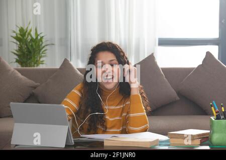 A CURLY HAIRED TEENAGER CHEERFULLY ATTENDING ONLINE CLASSES Stock Photo