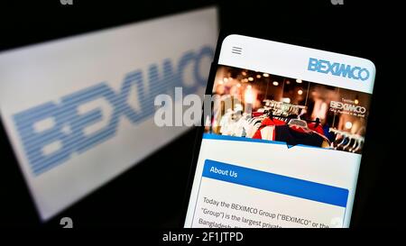 Mobile phone with website of Bangladesh Export Import Company Limited (BEXIMCO) on screen in front of logo. Focus on center of phone display. Stock Photo