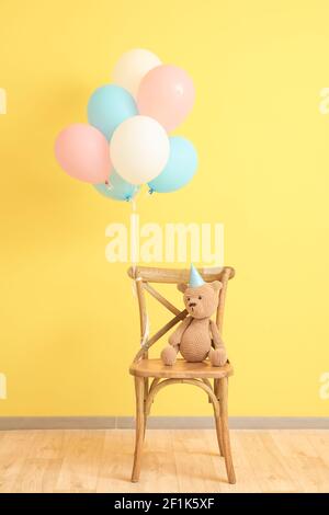 Air balloons with chair and teddy bear near color wall Stock Photo