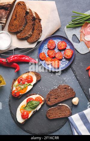 Preparing of tasty bruschettas with tomatoes on color background ...