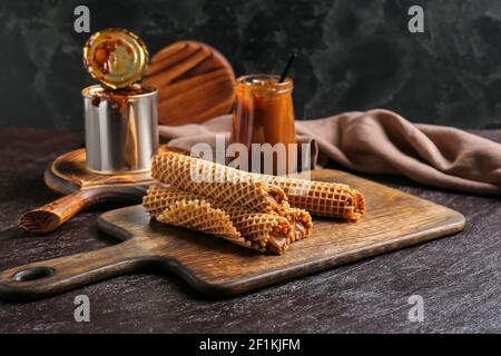 Tasty wafer rolls with boiled condensed milk on dark background Stock Photo