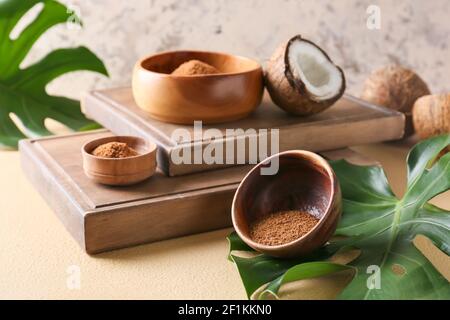 Bowls of sugar and sweet coconuts on color background Stock Photo