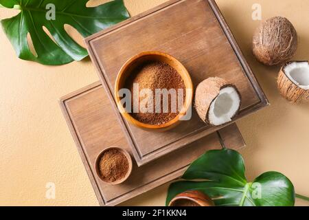 Bowls of sugar and sweet coconuts on color background Stock Photo
