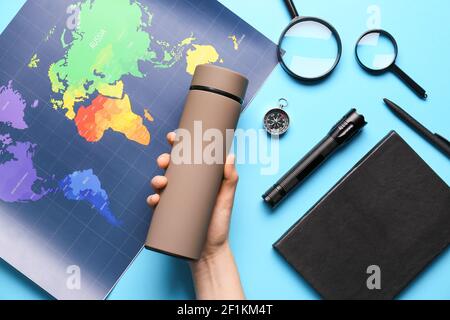 Female hand with modern thermos and world map on color background Stock Photo