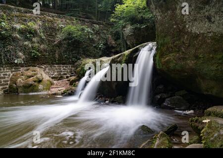 Idyllic small waterfall in lush green forest landscape Stock Photo