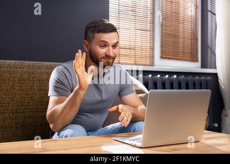 Young man online communication. He makes videocall chat talking with relatives or friends by video conference app. Online meeting of family. Remote Stock Photo