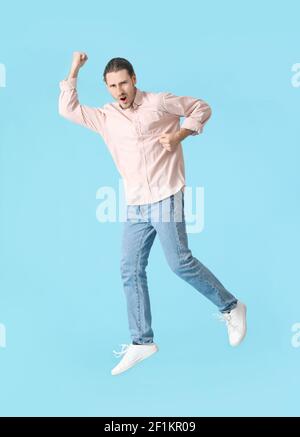 Jumping young man against color background Stock Photo