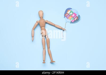 Wooden mannequin and paper air balloon with text APRIL FOOL'S on color background Stock Photo