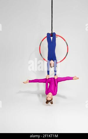 Two acrobat girls show a circus number on a dark background. Acrobatic ...