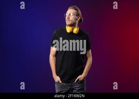 Handsome young man with headphones on dark background Stock Photo