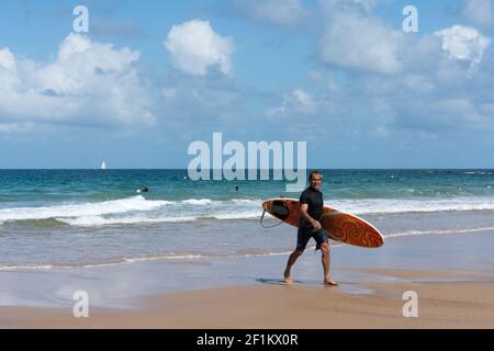 Middle-aged surfer walking on the beach after a fun surfing session in the waves on the coast of Bri Stock Photo
