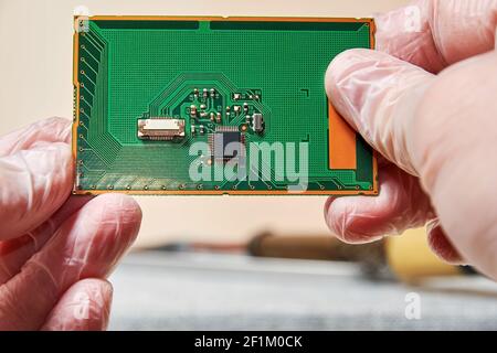 An engineer keeps and examines the PCB with a microchip in tech laboratory. Manufacturing and nanotechnology concept Stock Photo