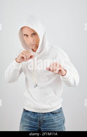Portrait of serious middle-aged man in white hoodie ready to fight Stock Photo