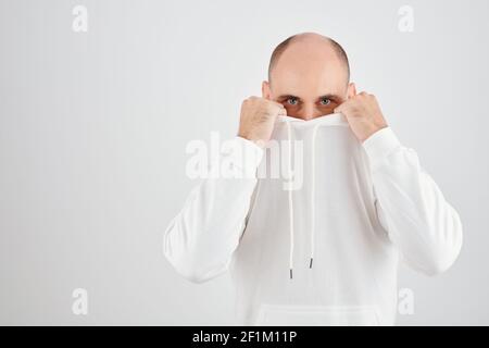 Portrait of handsome mature man covering face with hoodie and looking at camera Stock Photo
