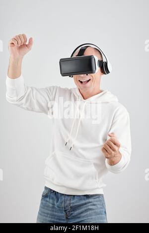 Portrait of happy excited mature man enjoying playing videogame in virtual reality headset Stock Photo