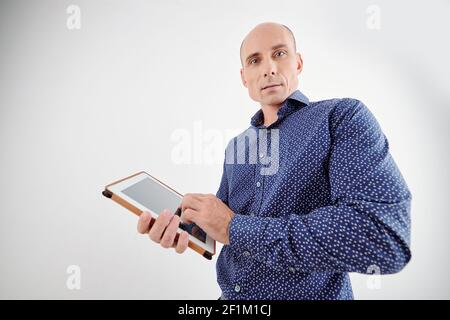 Portrait of handsome serious mature man standing with tablet computer in hands Stock Photo