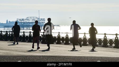 Brighton UK 9th March 2021 - Runners make the most of a beautiful sunny morning along Hove seafront as wet and stormy weather is forecast to arrive in the next few days throughout Britain : Credit Simon Dack / Alamy Live News